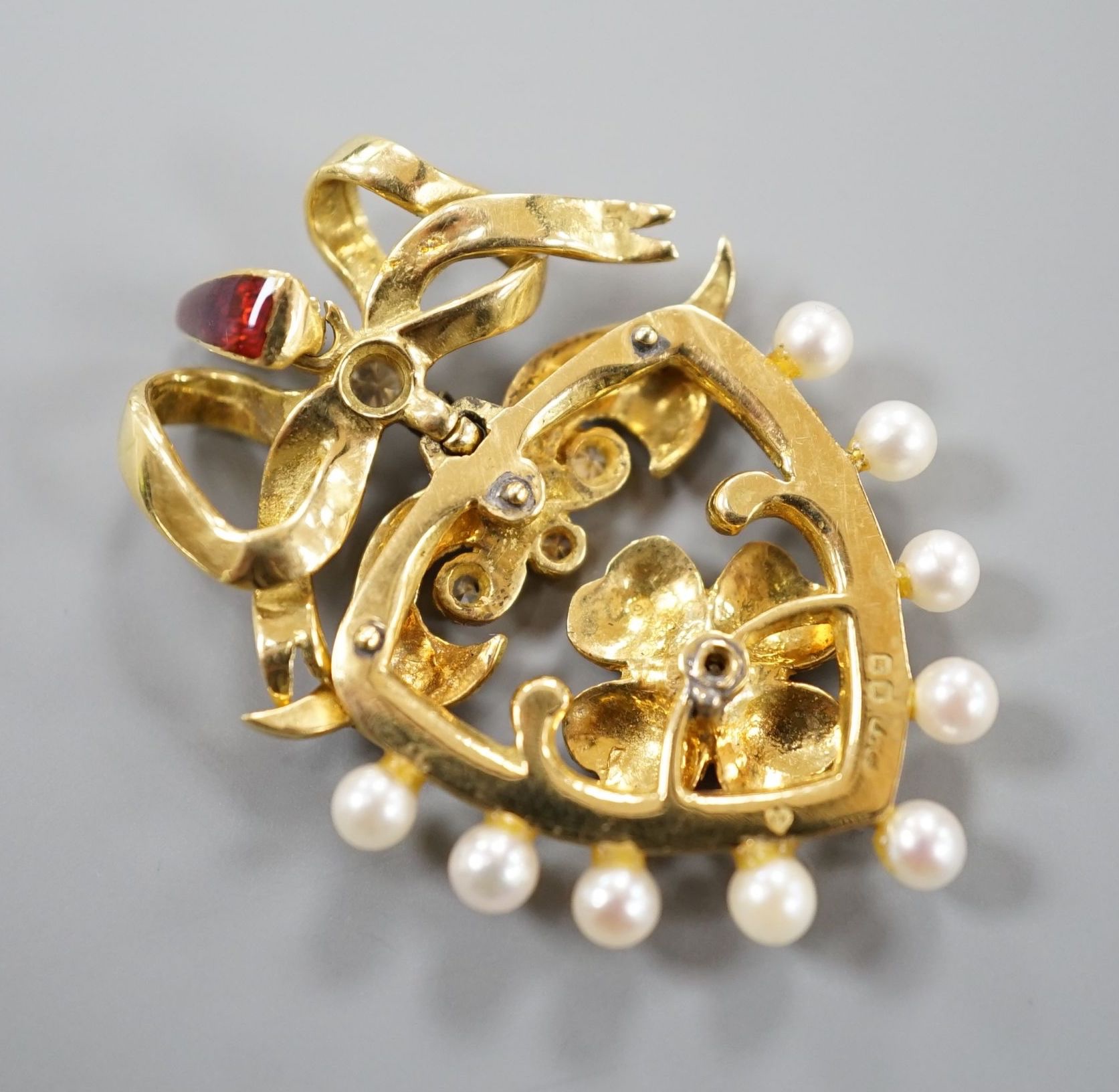 A 1960's 18ct gold, diamond, seed pearl and two colour enamel set heart shaped pendant, with ribbon bow crest, 35mm, gross weight 8.7 grams.
